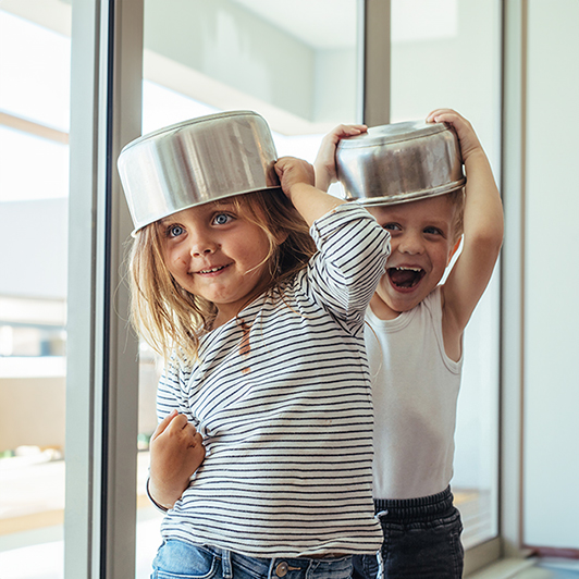 Schmuckbild: Zwei Kinder mit Töpfen auf dem Kopf